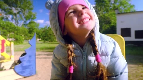 Beautiful child wearing a spring jacket and hat rides on balancing swing . Littl Stock Footage 278739267