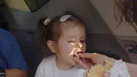 Beautiful children having breakfast while sitting on car trunk with burgers Stock Footage 249737175