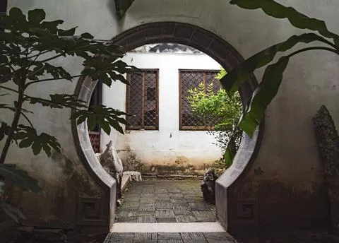 A beautiful circular arch frames a tranquil courtyard filled with greenery in an 写真素材