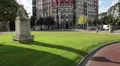 Beautiful city square with green lawns, modern buildings and historical monument HD Footage