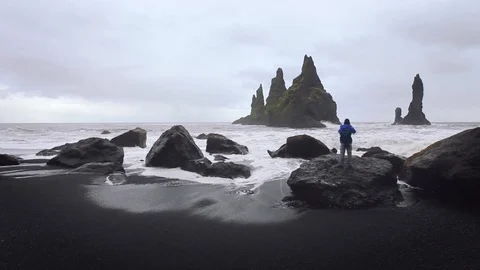 Beautiful cliffs in black sand beach in Iceland, tourist taking photo. Stock Footage 98419064
