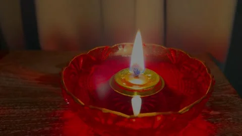 Beautiful close-up fire glow inside a red round oil lamp on table at home. Cozy Stock Footage 247400221
