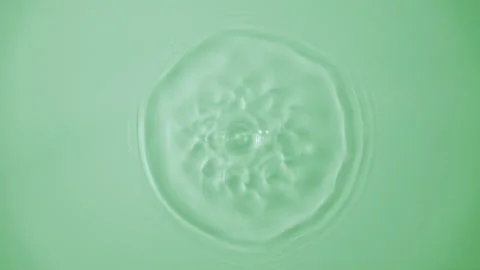 Beautiful closeup splash green serum drop. Slow motion rings and ripple top view Stock Footage 335876310