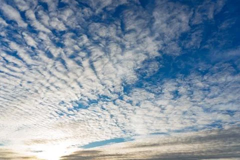 Beautiful cloud patterns fill the sky during sunset over a serene landscape Stock Photos