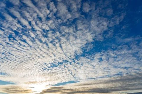 Beautiful cloud patterns lighting up the sky at sunset over the horizon Stock Photos