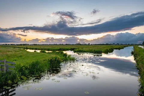 Beautiful clouds and calm water in the Dutch polder landscape at sunset Stock Photos