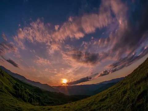 Beautiful clouds formastions at sunset, mountains in background and sun setting Stock Footage 76400404