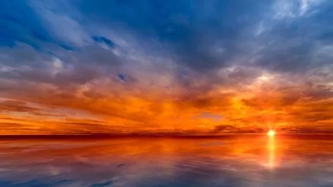 Beautiful cloudscape and sunset breaking through cloud over lake reflection. Stock Photos