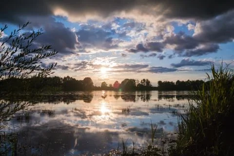 Beautiful cloudscape and sunset breaking through cloud over lake reflection Stock Photos