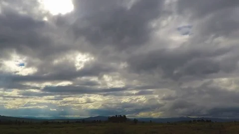 Beautiful cloudscape with large, building clouds and sunrise breaking through Stock Footage 76962992