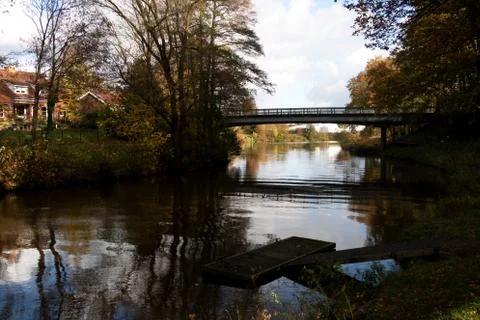 A beautiful cloudscape over a calm Ems canal with a narrow bridge walkway in  Stock Photos