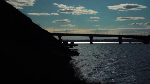 Beautiful cloudy sunset sky over bridge across calm river silhouette in steady Stock Footage 107334946