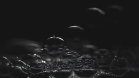 Beautiful colored bubbles in a liquid on a black background. Close-up. Slow Stock Footage 97848002