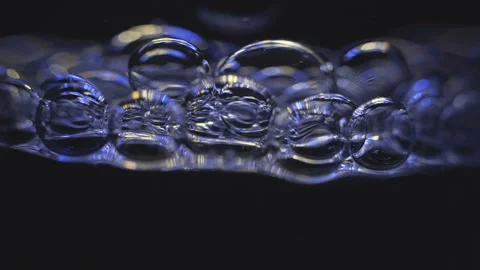 Beautiful colored bubbles in a liquid on a black background. Close-up. Slow Stock Footage 97849699