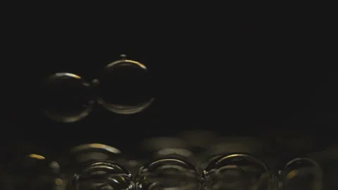 Beautiful colored bubbles in a liquid on a black background. Close-up. Slow Stock Footage 97849975