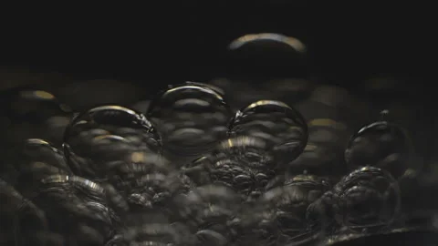 Beautiful colored bubbles in a liquid on a black background. Close-up. Slow Stock Footage 97850034