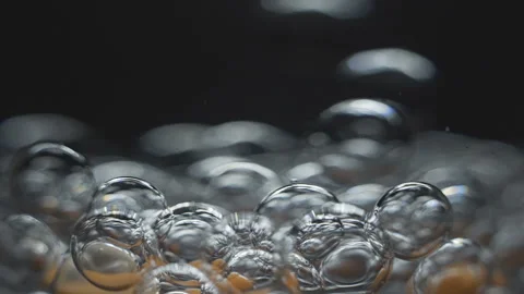 Beautiful colored bubbles in a liquid on a black background. Close-up. Slow Stock Footage 97852469