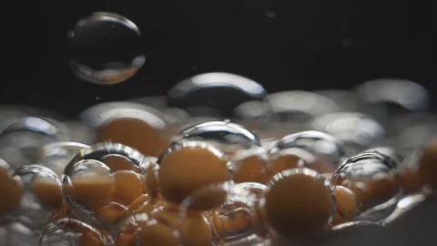 Beautiful colored bubbles in a liquid on a black background. Close-up. Slow Video stock 97852669