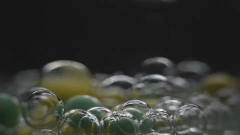 Beautiful colored bubbles in a liquid on a black background. Close-up. Slow Vídeo Stock 97853002