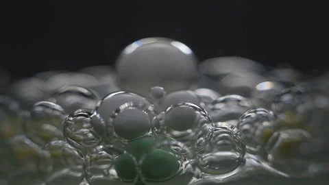 Beautiful colored bubbles in a liquid on a black background. Close-up. Slow Stock Footage 97853004