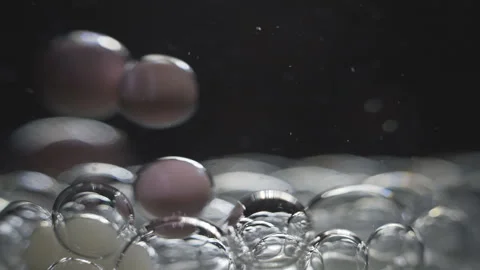 Beautiful colored bubbles in a liquid on a black background. Close-up. Slow Video stock 97853455