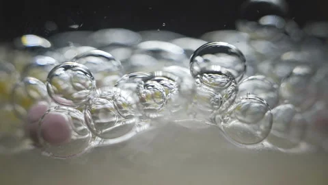 Beautiful colored bubbles in a liquid on a black background. Close-up. Slow Stock Footage 97853480