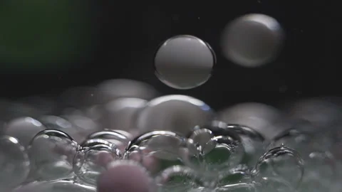 Beautiful colored bubbles in a liquid on a black background. Close-up. Slow Stock Footage 97853520