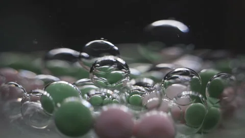 Beautiful colored bubbles in a liquid on a black background. Close-up. Slow Stock Footage 97853572