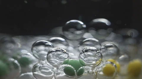 Beautiful colored bubbles in a liquid on a black background. Close-up. Slow Video stock 97853763