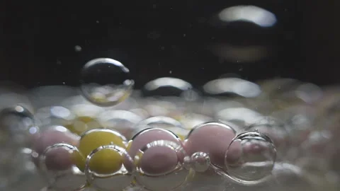 Beautiful colored bubbles in a liquid on a black background. Close-up. Slow Video stock 97853768