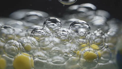 Beautiful colored bubbles in a liquid on a black background. Close-up. Slow Stock Footage 97853919