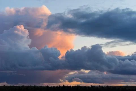 Beautiful colored dramatic stormy cumulus clouds on sky at sunset over fore.. Stock-Fotos