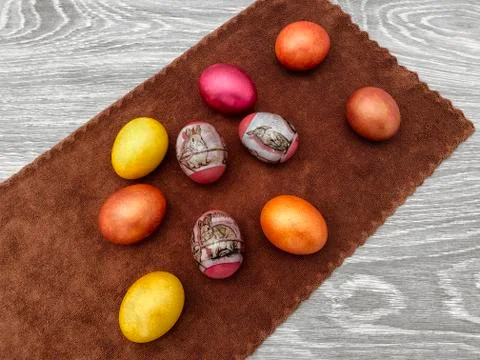 Beautiful colored Easter eggs on a brown rattle against a gray wooden table.  Stock Photos