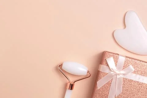 Beautiful composition of face roller, guasha and gift box Stock Photos