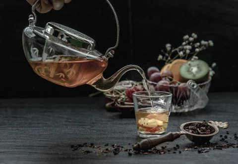 A Beautiful composition with Hot fruit tea is poured from the glass teapot .. Foto stock