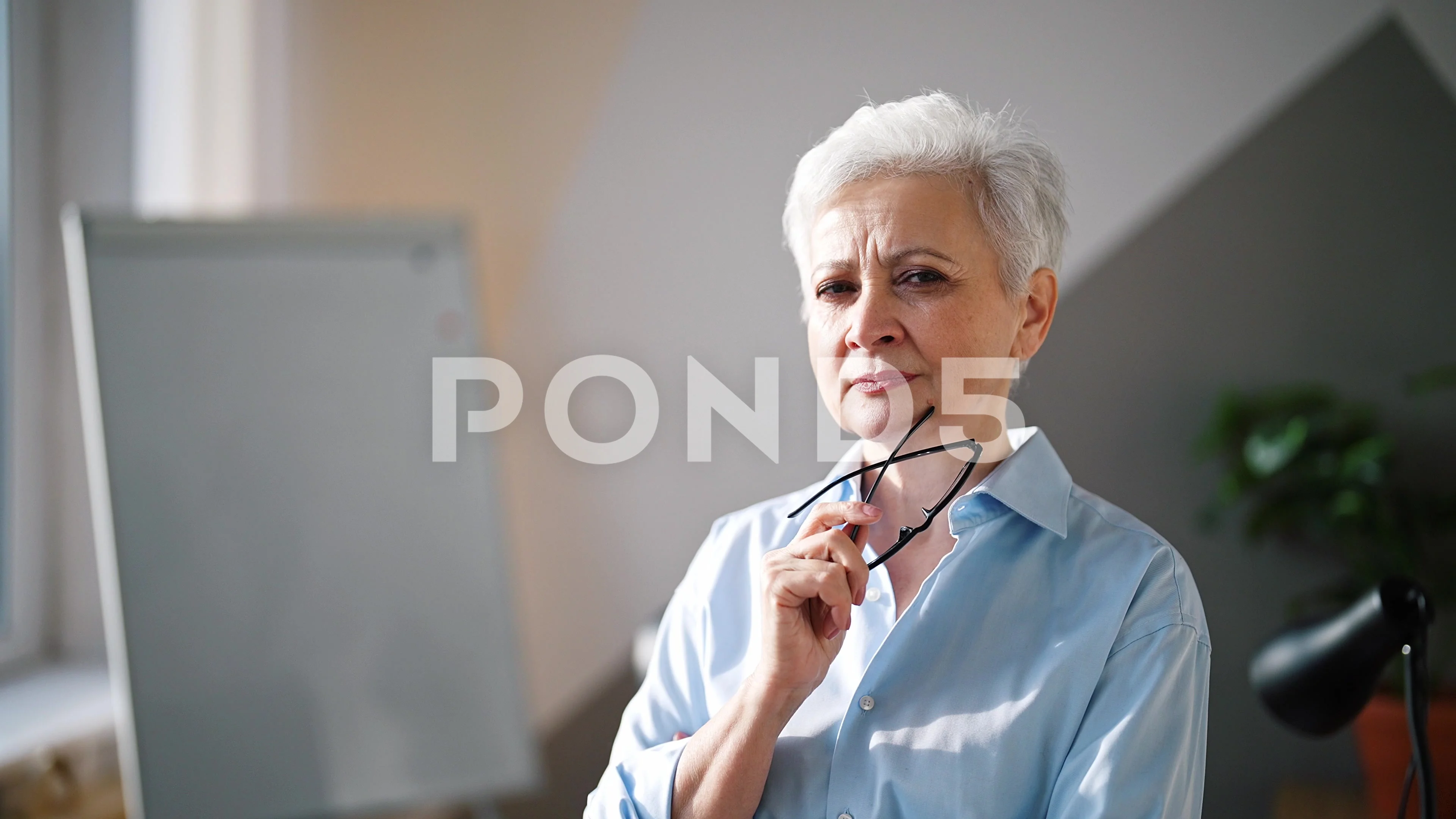 Beautiful, confident older woman taking off glasses and looking at camera