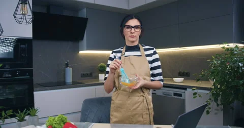 Beautiful confident young dark-haired woman posing on camera in modern cuisine Stock Footage 148747827