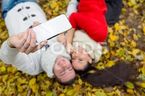 Beautiful couple in autumn park lying on the ground Stock Photos
