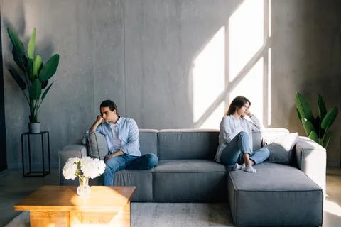Beautiful couple is having a quarrel while sitting on sofa at home Stock Photos