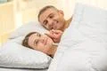 The beautiful couple lie on the bed and smile Photo
