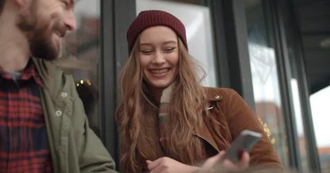 Beautiful couple looking at smartphone while sitting in outdoors restaurant. Stock Photos