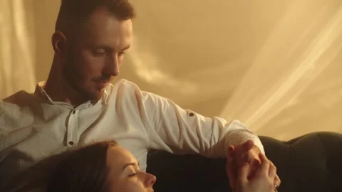 Beautiful couple lying on couch with hands together. Romance family relaxed at Stock Footage 253630073