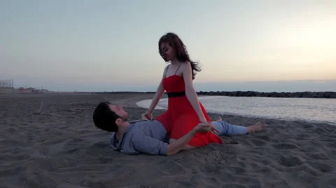 Beautiful couple lying down and kissing on the beach Stock Footage 32585558