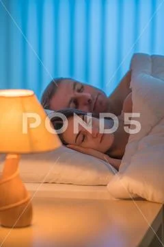 The beautiful couple sleeping on the bed. Evening night time Stock Photos