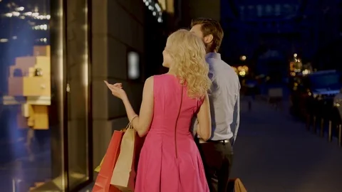 Beautiful couple strolling through evening market street looking at shop windows 스톡 동영상 80662654