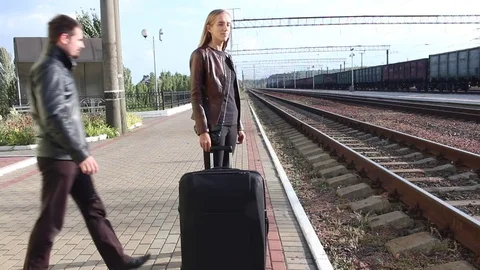 Beautiful couple walking with a suitcase on the platform Stock Footage 77076994