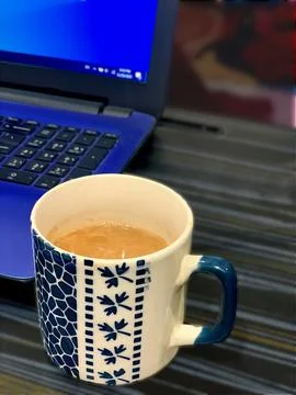 A beautiful cup of tea placed on the table with a laptop 3 Stock Photos
