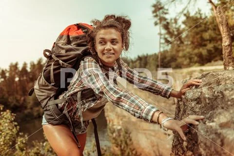 Beautiful curly woman holding on to the cliff Stock Photos