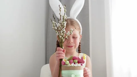 A beautiful, cute, smart girl in an Easter bunny costume smiles and holds a will Video stock 181612841