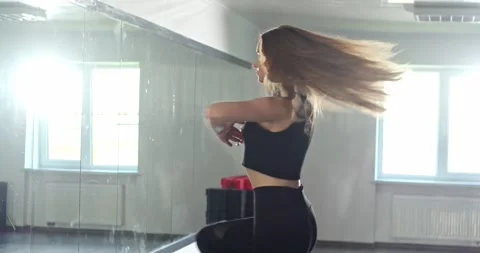 A beautiful dancer practices a dance in front of a mirror wall in the studio. Video stock 280479695